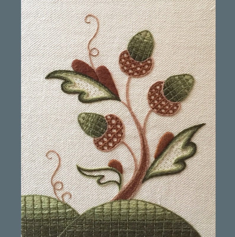 May include: Embroidered design of a stylized tree with brown branches and green leaves. The tree has three acorns with brown and green stitching.