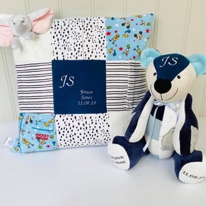 May include: A blue and white patchwork baby quilt with a blue and white striped border. The quilt has a blue square in the centre with the initials "JS" and the name "Jenson James" and the date "11.08.19". A blue and white patchwork teddy bear with the initials "JS" and the date "11.08.19" is sitting on the quilt. A small grey elephant with pink ears is on the quilt.