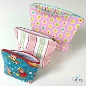 May include: Three zippered pouches in different sizes and patterns. The largest pouch is pink with a white polka dot pattern, the middle pouch is pink and white striped, and the smallest pouch is blue with a retro space-themed print.
