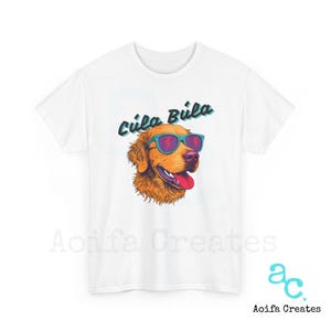 May include: White t-shirt with a graphic of a golden retriever wearing sunglasses and the text "Cula Bula" in a retro font.