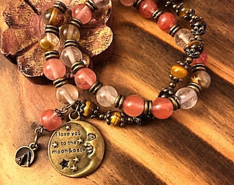 May include: A double-strand bracelet with pink, clear, and brown beads. The bracelet has a charm that says "I love you to the moon & back" with a crescent moon and stars.