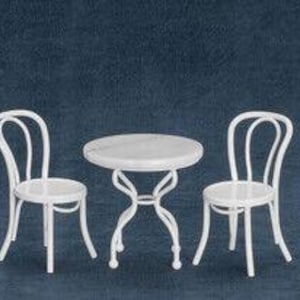 May include: A miniature white bistro set with a round table and two chairs. The table has a marble-like top and a decorative, curved base. The chairs feature curved backs and simple, round seats. The set is designed for a dollhouse or miniature setting.