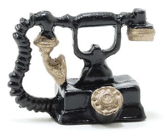 May include: A miniature black vintage telephone with a gold-colored receiver, mouthpiece, and dial. The cord is coiled. The telephone is set against a white background.