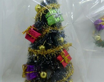 May include: A miniature Christmas tree with a gold star on top, decorated with small wrapped presents in red, green, and purple. The tree is adorned with gold tinsel and ornaments, and sits on a red base.