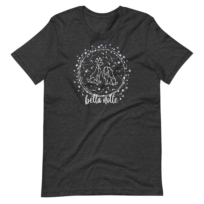 Puede incluir: Una camiseta gris oscuro jaspeada con un dise&ntilde;o blanco de tres perros en un c&iacute;rculo de constelaci&oacute;n. El texto "bella notte" est&aacute; debajo del c&iacute;rculo.