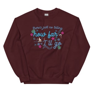 May include: A maroon sweatshirt with the text "there's just no telling how far I'll go" in turquoise script. The design includes tropical flowers, starfish, and a sailboat. The sweatshirt is a comfortable, casual style.