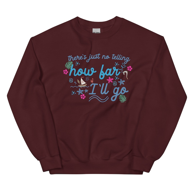 May include: A maroon sweatshirt with the text "there's just no telling how far I'll go" in turquoise script. The design includes tropical flowers, starfish, and a sailboat. The sweatshirt is a comfortable, casual style.