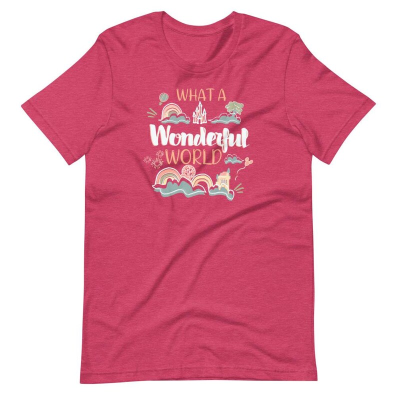 May include: A pink heather t-shirt with the text "What a Wonderful World" in a whimsical font. The text is surrounded by colorful illustrations of clouds, rainbows, and a castle.