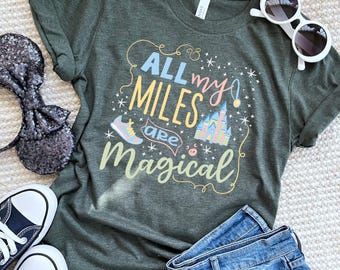 Może przedstawiać: Zielona koszulka z napisem "All my miles are magical" w kolorowych literach. Projekt zawiera but do biegania, zamek i gwiazdy.