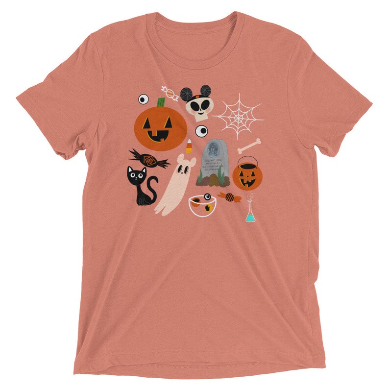 K&ouml;nnte beinhalten: Pfirsichfarbenes T-Shirt mit kurzen &Auml;rmeln und einem Halloween-Motiv. Das Design zeigt einen K&uuml;rbis, eine schwarze Katze, einen Geist, S&uuml;&szlig;igkeiten, ein Spinnennetz, einen Totenkopf und einen Grabstein. Das T-Shirt ist aus weichem, bequemem Material.