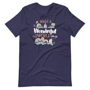 May include: Navy blue t-shirt with a whimsical illustration of a castle, clouds, rainbows, and a hot air balloon. The text "What a Wonderful World" is printed in orange on the shirt.