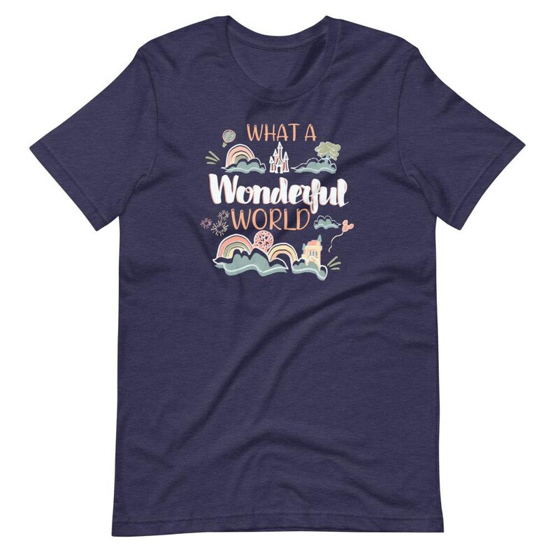 May include: Navy blue t-shirt with a whimsical illustration of a castle, clouds, rainbows, and a hot air balloon. The text "What a Wonderful World" is printed in orange on the shirt.