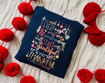 May include: A dark blue sweatshirt with a white and colorful graphic print that reads "...and EVERY night will end & every day will START with a grateful prayer AND a THANKFUL heart".