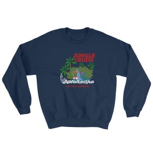 May include: Navy blue sweatshirt with a Jungle Cruise design. The graphic includes the text "JUNGLE CRUISE" in red, palm trees, and a boat scene with the text "ADVENTURELAND" and "daily cruises departing daily" in white.