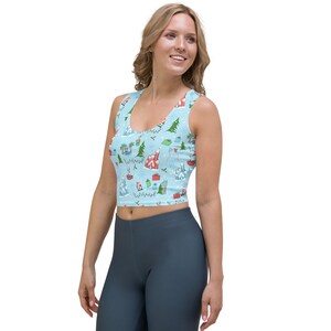 May include: Light blue crop top with a festive pattern featuring houses, palm trees, gifts, and snowflakes. The sleeveless top is made of a soft material and is designed for comfort. The top is a great addition to any wardrobe.