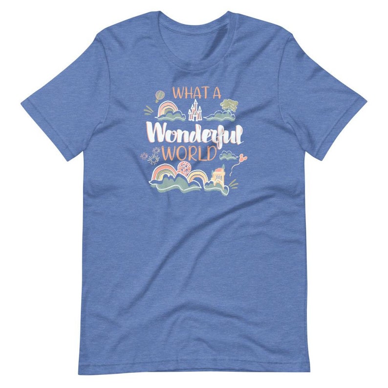 May include: A blue t-shirt with the text "What a Wonderful World" in pink and orange lettering. The shirt features a whimsical design with a castle, rainbows, and clouds.