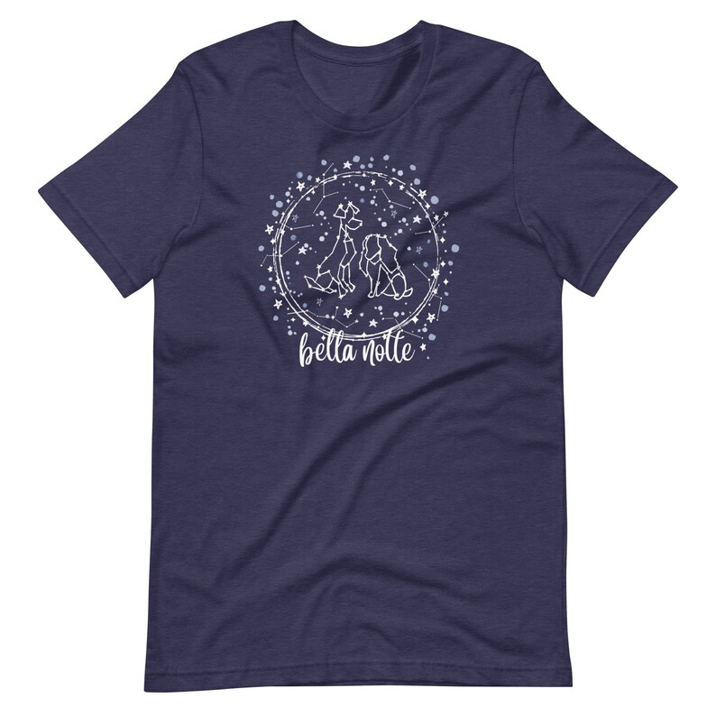 Puede incluir: Una camiseta azul marino con un dise&ntilde;o blanco de tres perros en un c&iacute;rculo de constelaci&oacute;n. El texto "bella notte" est&aacute; debajo del c&iacute;rculo.
