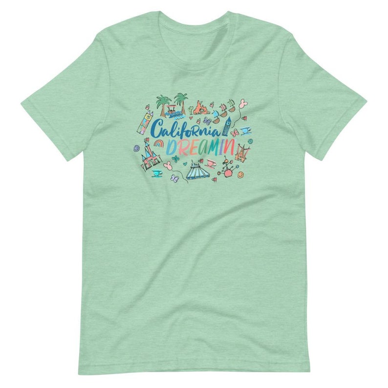 May include: A light green t-shirt with a colorful illustration of a California theme park. The text "California Dreamin'" is written in a rainbow font.
