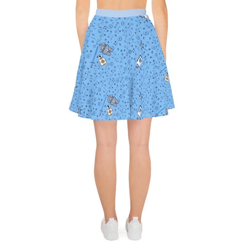 Puede incluir: Una falda skater azul claro con un patr&oacute;n de personajes de Star Wars, incluyendo Darth Vader, R2-D2 y BB-8. La falda tiene una cintura blanca.