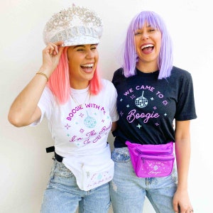 May include: Two people wearing matching outfits. One wears a white t-shirt with "BOOGIE WITH ME I'm The Bride To Be" and a white fanny pack. The other wears a black t-shirt with "WE CAME TO Boogie" and a purple fanny pack. Both are wearing light blue jeans.