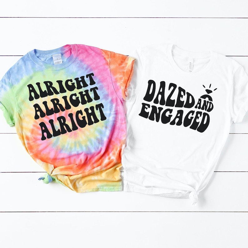 May include: Two tie-dye t-shirts with a retro font design. One shirt is a rainbow tie-dye with the text "Alright Alright Alright". The other shirt is white with the text "Dazed and Engaged".
