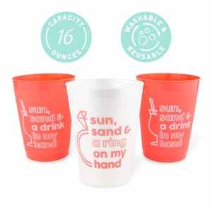 May include: Three plastic cups, two in coral and one in white. The coral cups have the text "sun, sand & a drink in my hand." The white cup has the text "sun, sand & a ring on my hand." Each cup has a 16-ounce capacity.