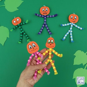 May include: Five pumpkin people made with pipe cleaners and orange pumpkin faces. The pumpkin people are in various colors, including green, purple, blue, pink, and yellow.
