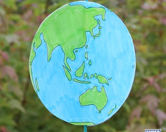 May include: A blue and green paper craft of the Earth hanging from a string. The continents of Asia, Australia, and parts of Africa are visible.