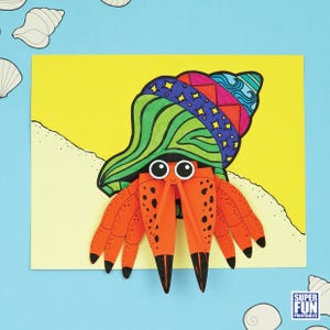 May include: A colorful paper craft of a hermit crab with a patterned shell and orange body. The crab is set against a yellow background with a sandy beach design. The image includes the text "SUPER FUN PRINTABLES".