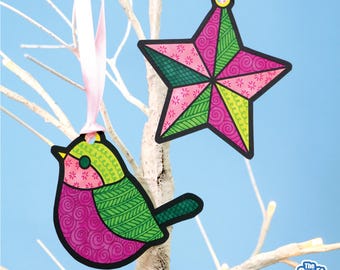 May include: Two colorful Christmas ornaments hanging from a white tree branch. One is a bird shape, and the other is a star shape. Both ornaments have pink, green, and black accents. The bird ornament has a pink body and green wings. The star ornament has pink and green sections.
