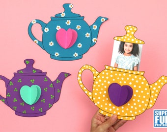 May include: Three paper teapots with different patterns and colors. The teapots have a heart-shaped cutout on the front. One teapot has a photo of a child inside.