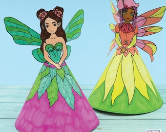 May include: Two paper fairy dolls with wings and cone-shaped dresses. The fairy on the left has green wings and a pink and green dress. The fairy on the right has orange wings and a yellow and green dress.