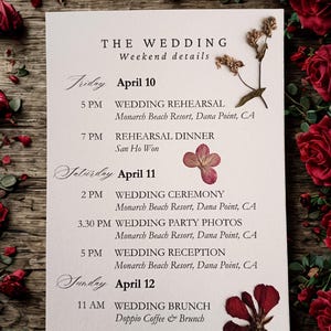 Puede incluir: Una tarjeta de detalles del fin de semana de boda con un diseño floral. La tarjeta enumera el programa de la boda, incluyendo el ensayo, la ceremonia, la recepción y el brunch. La tarjeta está decorada con flores secas y rodeada de rosas rojas.