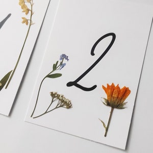Cartellini segnatavolo con fiori pressati. Numeri segnatavolo per matrimonio con fiori. Cartellini per decorazioni per matrimonio con fiori pressati. Matrimoni in giardino.