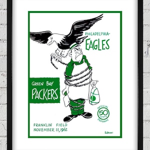 May include: A vintage green and black illustration of a Green Bay Packers fan tied up by a Philadelphia Eagles fan. The text reads "Green Bay Packers", "Philadelphia Eagles", "Franklin Field", "November 11, 1962", and "Official 50 Cents Program".
