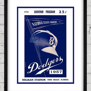 Könnte beinhalten: Ein Vintage-Programm in Blau und Weiß für das Baseballteam der Dodgers aus dem Jahr 1957. Das Programm zeigt eine Baseballkappe mit dem Teamlogo und dem Text "National League Champions". Das Programm enthält auch den Text "Dodgers 1957" und "Holman Stadium Vero Beach, Florida".