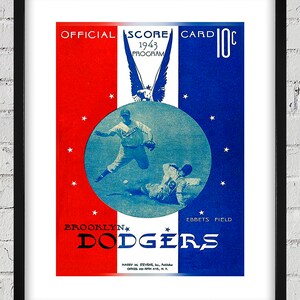 May include: A vintage 1943 Brooklyn Dodgers scorecard with a red, white, and blue color scheme. The card features an illustration of two baseball players in action, with the team's name and the words "Official Score Card 10c" printed on the front.