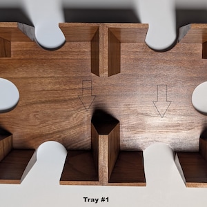 May include: A wooden tray with a puzzle-piece design. The tray is made of dark brown wood and features several compartments and cutouts. The text "Tray #1" is at the bottom of the image. Arrows point to the compartments.