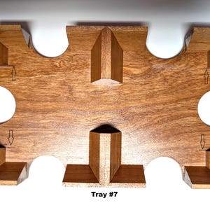 Puede incluir: Bandeja de madera con acabado natural. La bandeja tiene una forma única con cortes curvos y secciones elevadas. El texto "Tray #7" está impreso en la parte inferior de la bandeja. La bandeja está diseñada para contener objetos.