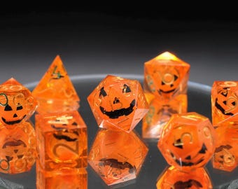 May include: A set of orange and black dice with a pumpkin face design. The dice are made of clear plastic with a glittery finish.