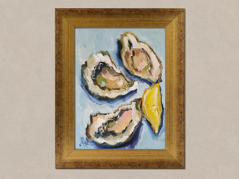 May include: An oil painting in a gold-toned frame depicting two open oysters and a yellow lemon wedge against a light blue background. The artwork features visible brushstrokes and a signature in the bottom left corner of the canvas.