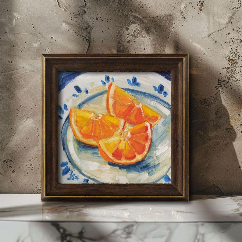 Original oil painting of juicy orange slices, elegantly presented in a frame. The artwork is captured in a vibrant impressionist style with bold, thick brushstrokes that highlight the glistening texture of the fruit. Featuring a bright citrus palette and a beautiful play of light, this small fruit still life is a perfect pop of color for a modern kitchen or a sunny dining room wall.
