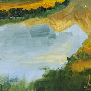 May include: An oil painting on canvas depicting a landscape with a central light blue body of water surrounded by textured brushstrokes of yellow, gold, and deep green foliage. A signature in cursive yellow paint is visible in the bottom right corner.