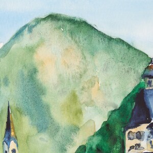 Puede incluir: Pintura a la acuarela de un paisaje de monta&ntilde;a con una iglesia y un campanario. La pintura presenta una gran monta&ntilde;a verde, un cielo azul y edificios con tejados azul oscuro. El estilo es suave e impresionista.