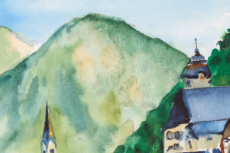 Puede incluir: Pintura a la acuarela de un paisaje de monta&ntilde;a con una iglesia y un campanario. La pintura presenta una gran monta&ntilde;a verde, un cielo azul y edificios con tejados azul oscuro. El estilo es suave e impresionista.