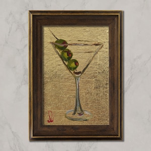 May include: A framed painting of a martini glass with three olives. The glass is filled with a clear liquid and sits against a gold background. The frame is dark brown.
