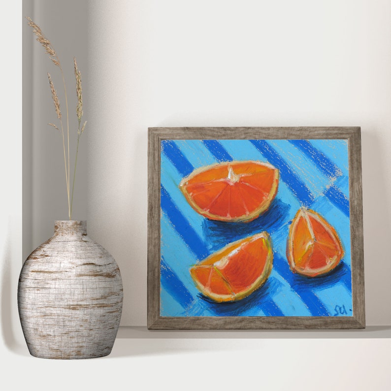 May include: A framed painting of three orange slices on a blue and white striped background. The painting is signed "S.U."