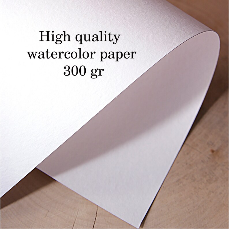 Puede incluir: Primer plano de una pila de papel de acuarela blanco. El texto en el papel dice "High quality watercolor paper 300 gr". El papel est&aacute; ligeramente curvado, revelando su grosor y textura.