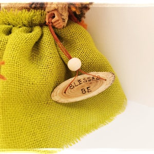May include: A green burlap doll with a wooden sign that says "Blessed Be".