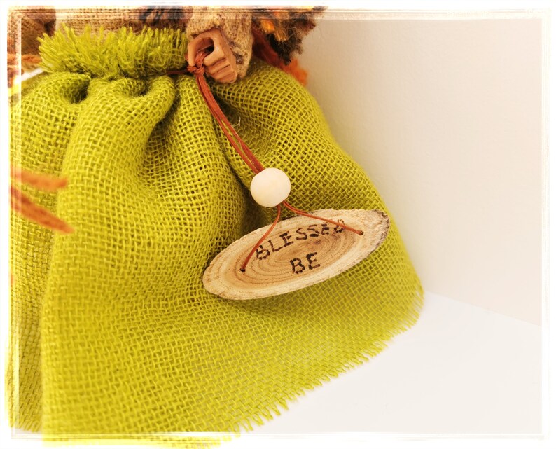 May include: A green burlap doll with a wooden sign that says "Blessed Be".